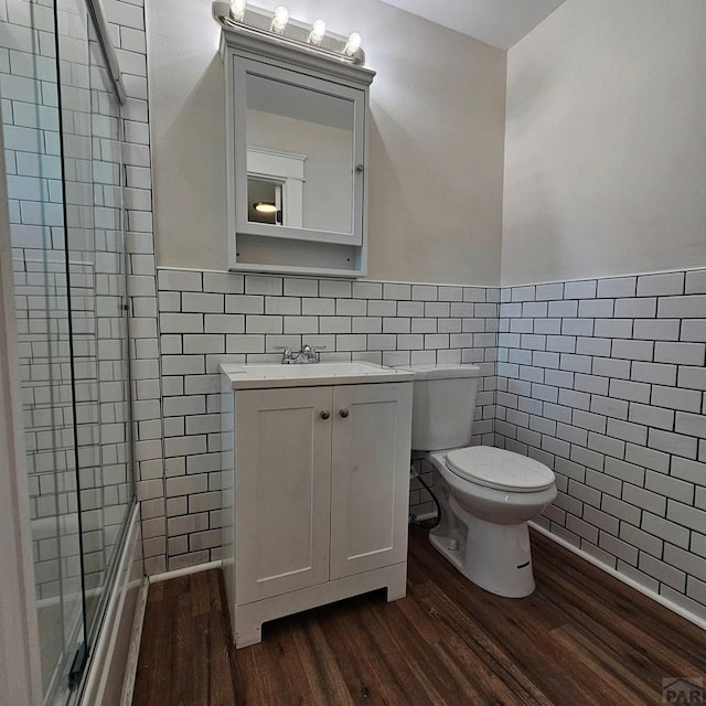 1938 E 6th St, Pueblo, CO 81001 - full bath with tile walls, wood finished floors, an enclosed shower, vanity, and wainscoting