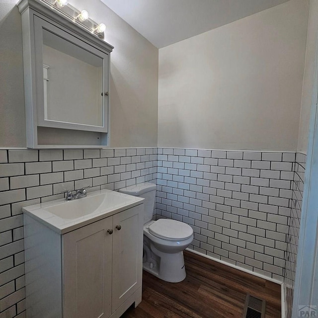 1938 E 6th St, Pueblo, CO 81001 - half bathroom featuring tile walls, vanity, wood finished floors, and a wainscoted wall