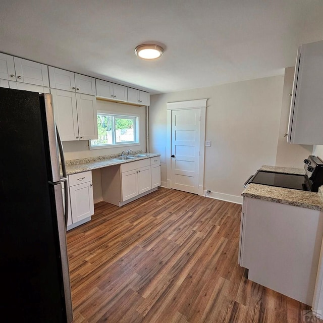 1938 E 6th St, Pueblo, CO 81001 - kitchen with freestanding refrigerator, range with electric cooktop, wood finished floors, and white cabinetry