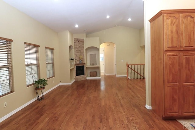 746 E Paseo Dorado Dr, Pueblo West, CO 81007 - unfurnished living room with wood finished floors, vaulted ceiling, a fireplace, arched walkways, and recessed lighting
