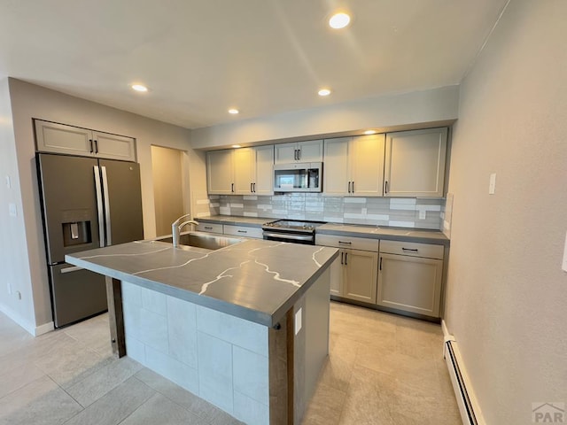 476 S Hahns Peak Ave, Pueblo West, CO 81007 - kitchen with stainless steel appliances, decorative backsplash, an island with sink, recessed lighting, and baseboard heating