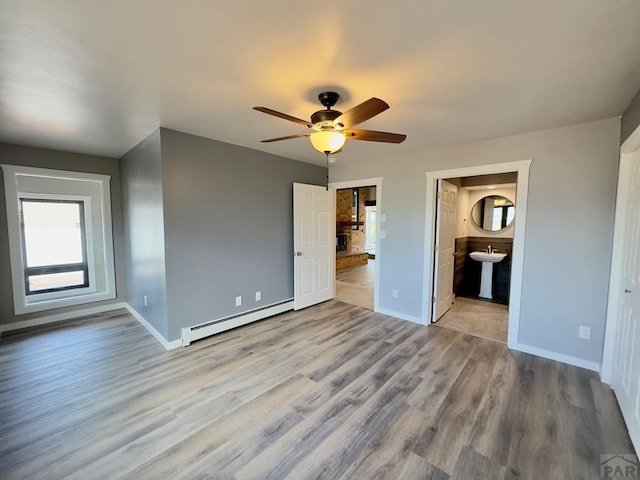 476 S Hahns Peak Ave, Pueblo West, CO 81007 - unfurnished bedroom featuring baseboard heating, wood finished floors, multiple windows, and connected bathroom