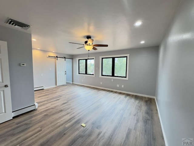 476 S Hahns Peak Ave, Pueblo West, CO 81007 - empty room with baseboard heating, a barn door, wood finished floors, a ceiling fan, and recessed lighting