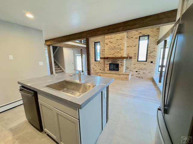476 S Hahns Peak Ave, Pueblo West, CO 81007 - kitchen featuring freestanding refrigerator, open floor plan, an island with sink, a fireplace, and brick wall
