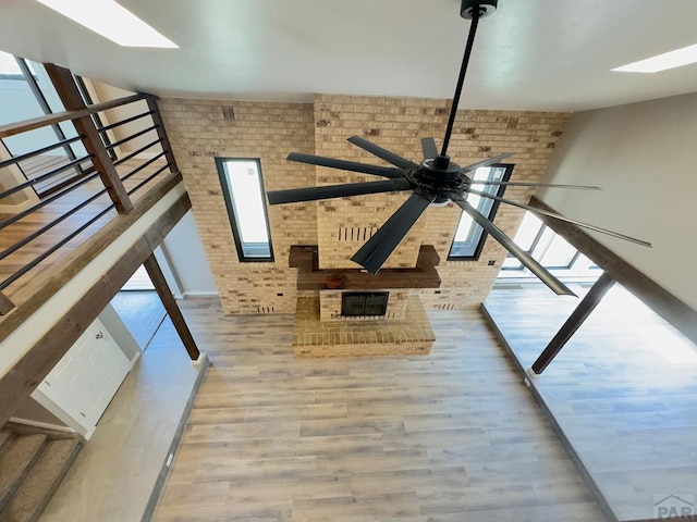 476 S Hahns Peak Ave, Pueblo West, CO 81007 - unfurnished living room featuring brick wall, a skylight, wood finished floors, a ceiling fan, and stairway