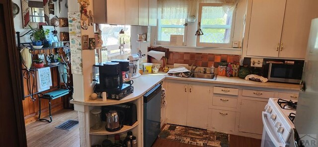 kitchen featuring black dishwasher, white gas range, light countertops, stainless steel microwave, and a sink