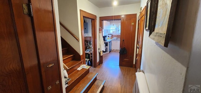 hallway with stairway, wood finished floors, and electric panel