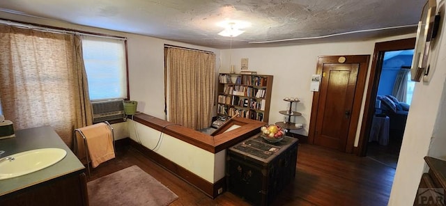 interior space with dark wood-style flooring, cooling unit, a sink, and baseboards