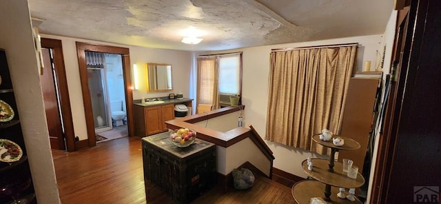 hall with baseboards, a sink, and wood finished floors