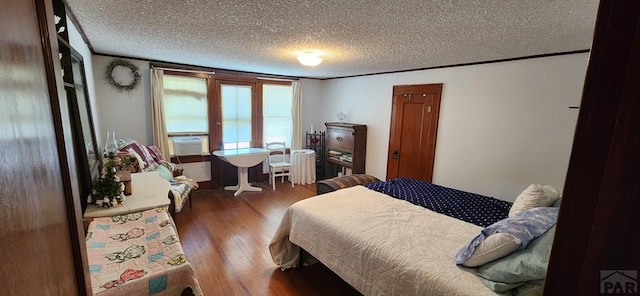 bedroom with crown molding, a textured ceiling, cooling unit, and wood finished floors