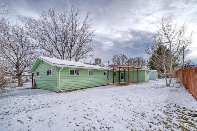 snow covered rear of property featuring fence and central AC