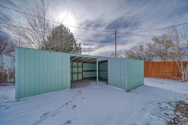 snow covered structure featuring a pole building, fence, and an outdoor structure