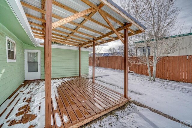 snow covered deck with an outdoor structure and a fenced backyard