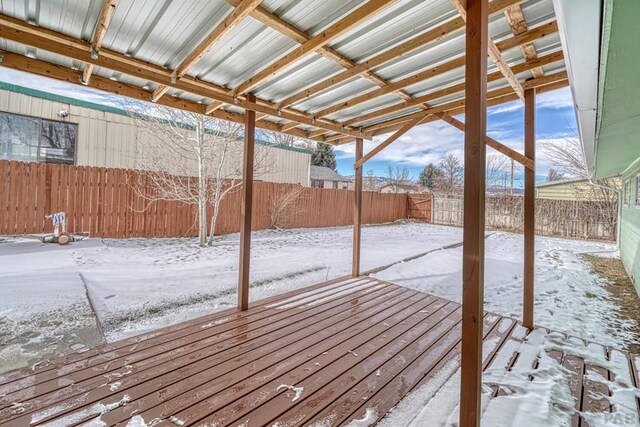 snow covered deck with a fenced backyard