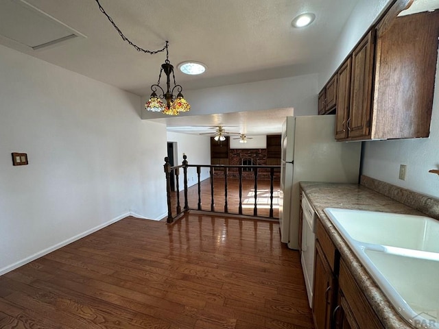 kitchen with a sink, light countertops, white dishwasher, and dark wood finished floors