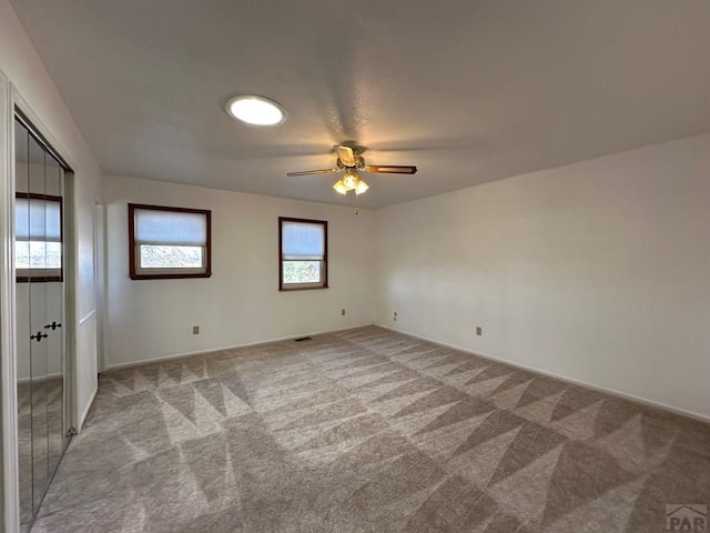 empty room featuring light colored carpet and ceiling fan