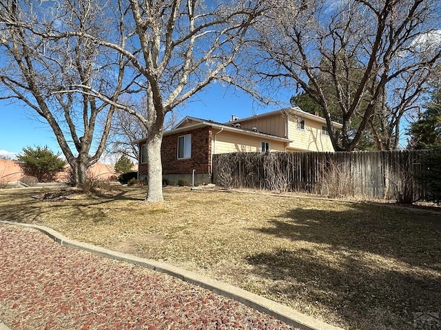 view of property exterior with fence and brick siding