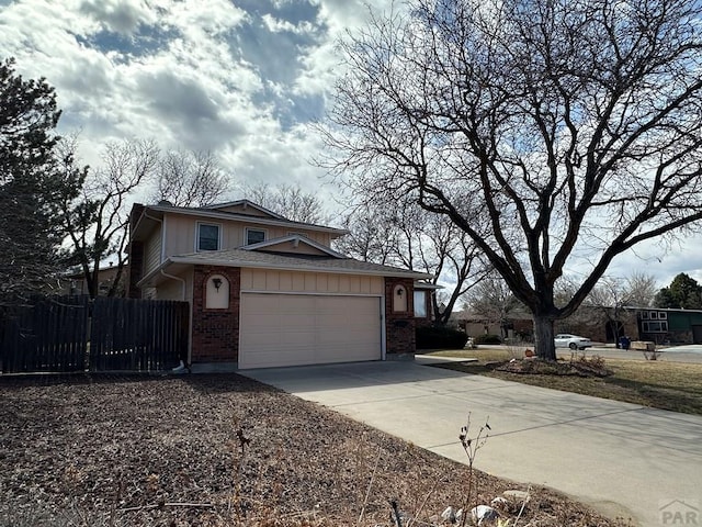 view of front of property featuring driveway, a garage, fence, and brick siding