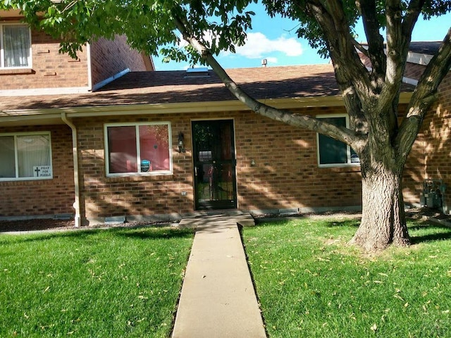 doorway to property with a lawn and brick siding