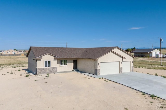 single story home featuring concrete driveway, a garage, stucco siding, and stone siding