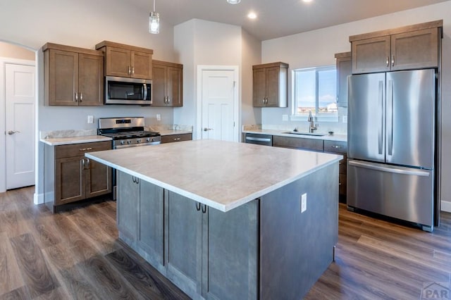 kitchen with a sink, a center island, appliances with stainless steel finishes, and dark wood-style floors