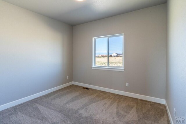 spare room featuring baseboards, visible vents, and carpet floors