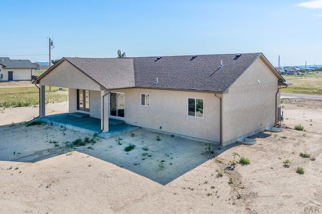 rear view of property featuring a patio area, french doors, a shingled roof, and stucco siding