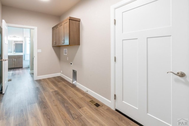 laundry room featuring baseboards, electric dryer hookup, washer hookup, cabinet space, and wood finished floors