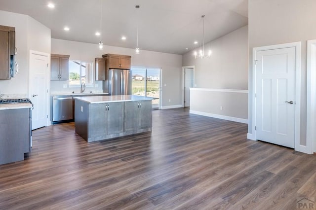 kitchen with an inviting chandelier, a kitchen island, appliances with stainless steel finishes, dark wood-style flooring, and light countertops
