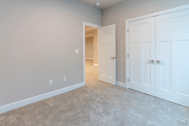 unfurnished bedroom with a closet, carpet flooring, and baseboards