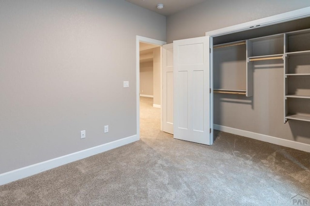 unfurnished bedroom with a closet, baseboards, and carpet flooring