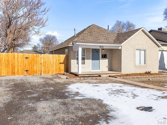 view of front of home with a shingled roof, a gate, fence, and stucco siding