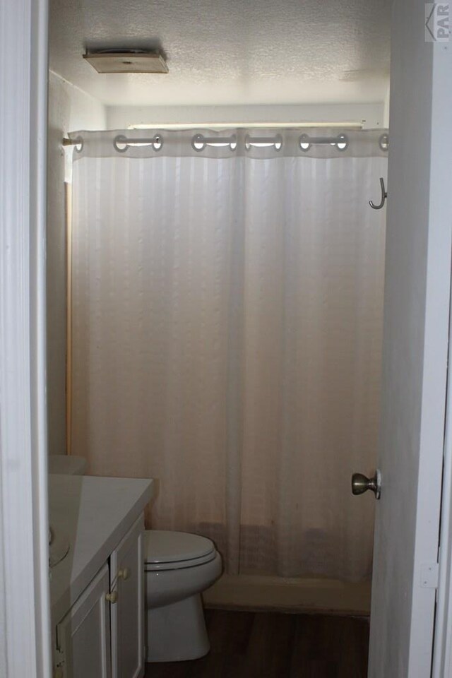 bathroom with toilet, curtained shower, a textured ceiling, and vanity