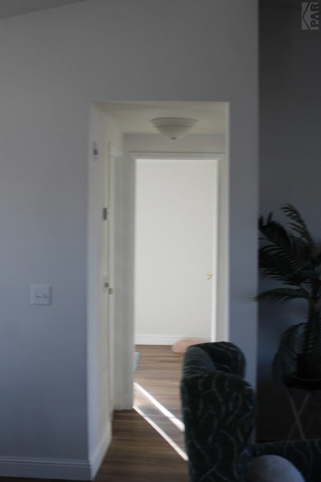 hallway with dark wood-type flooring and baseboards