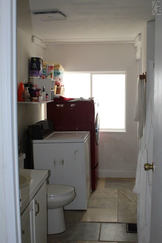 bathroom with toilet, vanity, and washer and dryer