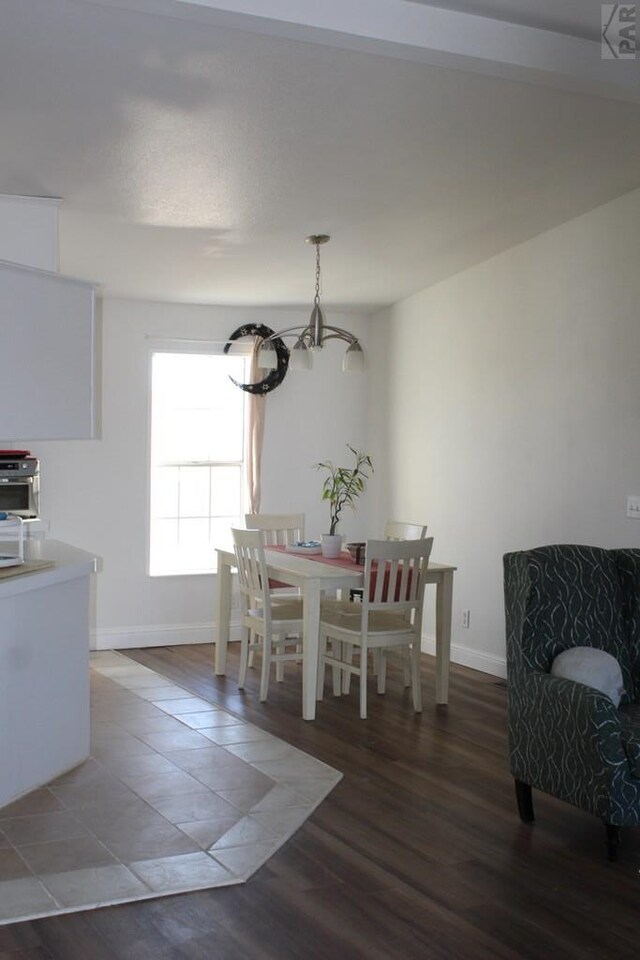 dining area featuring baseboards, dark wood finished floors, and a chandelier