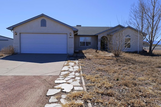 ranch-style home with driveway, an attached garage, and stucco siding