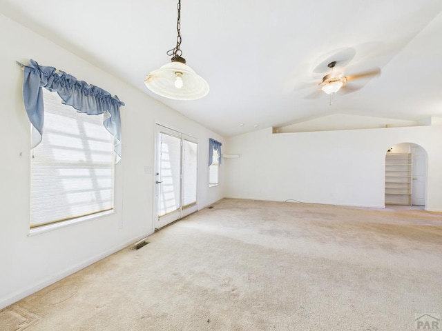 unfurnished room featuring carpet floors, ceiling fan, arched walkways, and vaulted ceiling