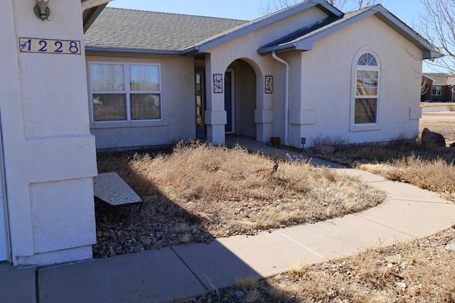 view of front of home with a shingled roof and stucco siding