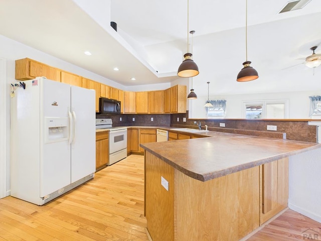 kitchen with white appliances, tasteful backsplash, a peninsula, light wood-type flooring, and a sink