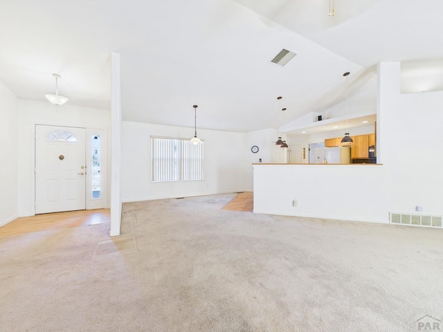 unfurnished living room with high vaulted ceiling, light colored carpet, and visible vents