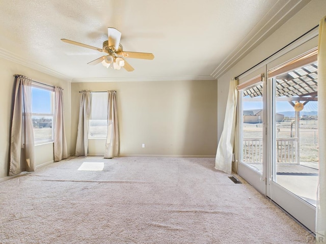 carpeted spare room with ceiling fan, a textured ceiling, baseboards, and crown molding