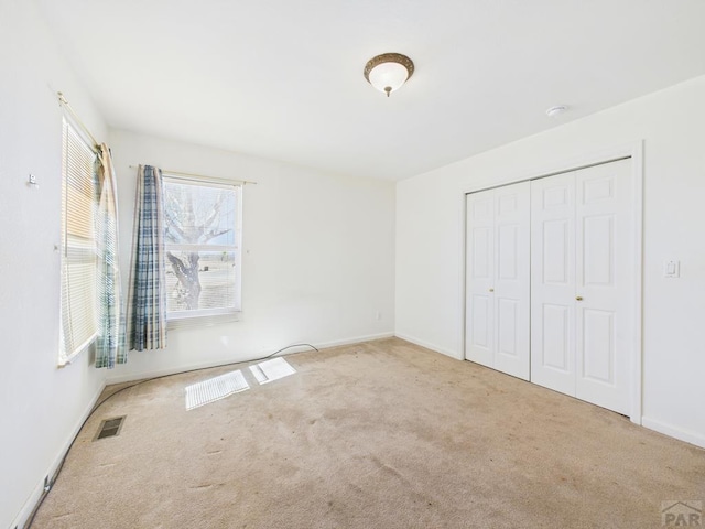 unfurnished bedroom featuring a closet, carpet flooring, visible vents, and baseboards