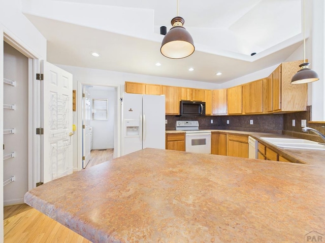 kitchen with white appliances, a sink, hanging light fixtures, and decorative backsplash