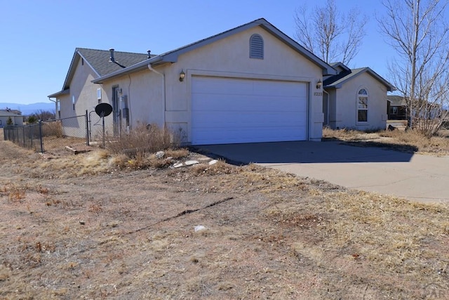 view of property exterior with a garage, concrete driveway, fence, and stucco siding