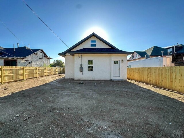 rear view of house featuring fence and stucco siding