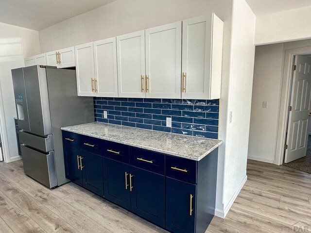 kitchen with tasteful backsplash, light wood-style floors, stainless steel fridge with ice dispenser, and blue cabinets