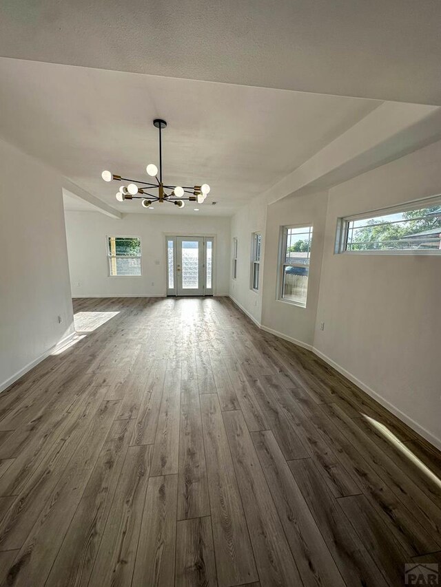 unfurnished living room featuring dark wood-style floors, baseboards, and an inviting chandelier