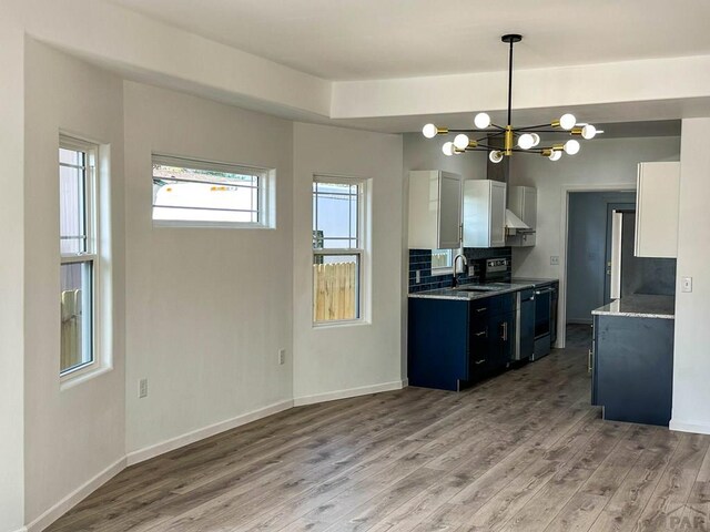 kitchen featuring baseboards, decorative backsplash, electric range oven, light wood-type flooring, and a sink