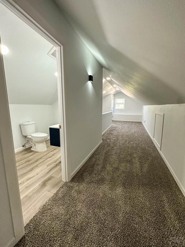 bonus room featuring lofted ceiling, carpet flooring, a textured ceiling, and baseboards